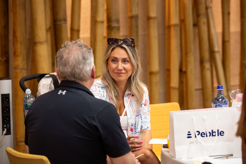 Two attendees networking with sponsor gift bags on the table